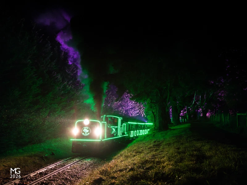 Green and Purple After struggling up the long climb from Cockatoo on wet rails, Puffing Billy's "Train of Lights" train crests the grade at Orchard Road on the outskirts of Gembrook.
